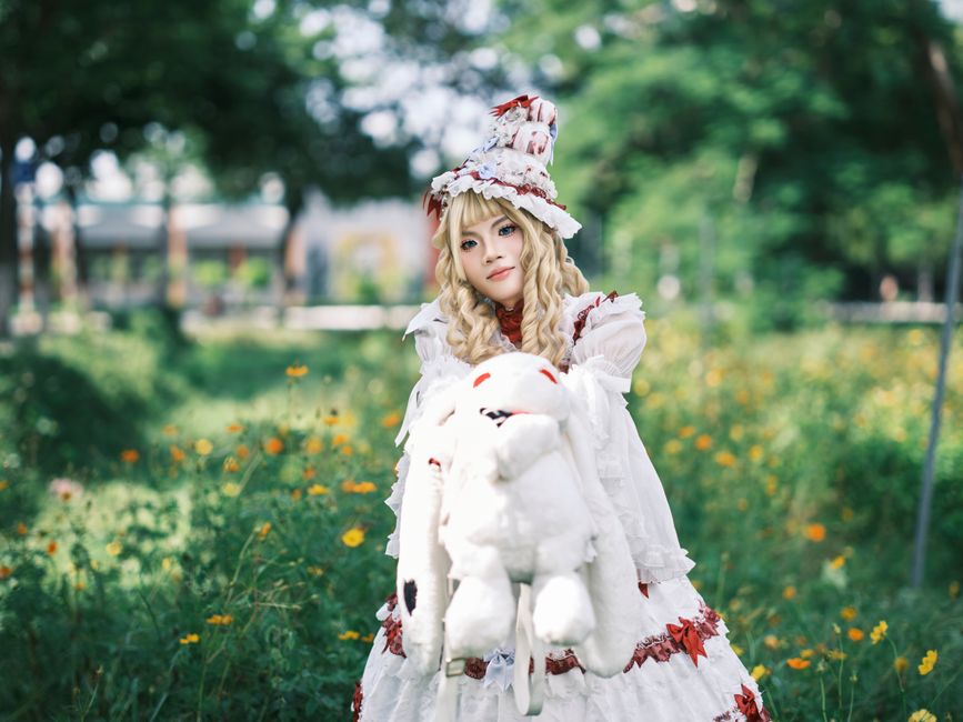 A fantasy character in an ornate costume stands in a vibrant outdoor setting, exuding whimsy and mystery.