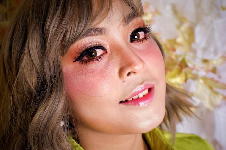 A close-up portrait of a woman with striking makeup, highlighting her eyes and skin tone.