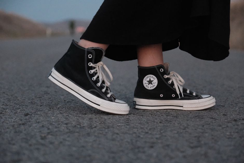 Close-up of a woman's feet in black high-top sneakers on a road.