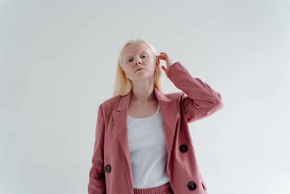 Studio portrait of a woman with blonde hair wearing a pink blazer and white top.