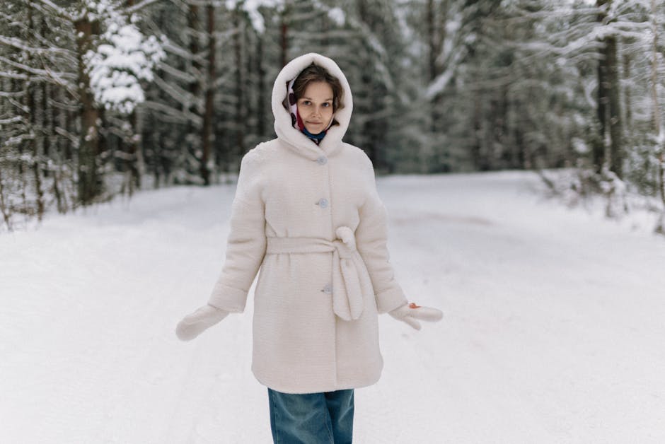 Woman in white coat standing in a snowy Belarus forest during winter.