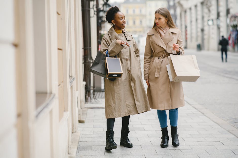 Two women in coats converse while shopping on a city street, showcasing diversity and winter fashion.