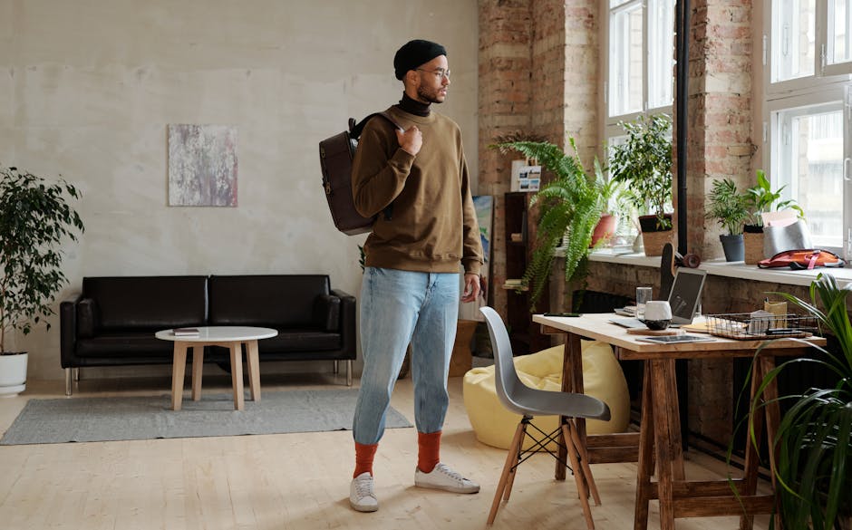 Stylish man with backpack in an urban loft office, showcasing modern fashion.