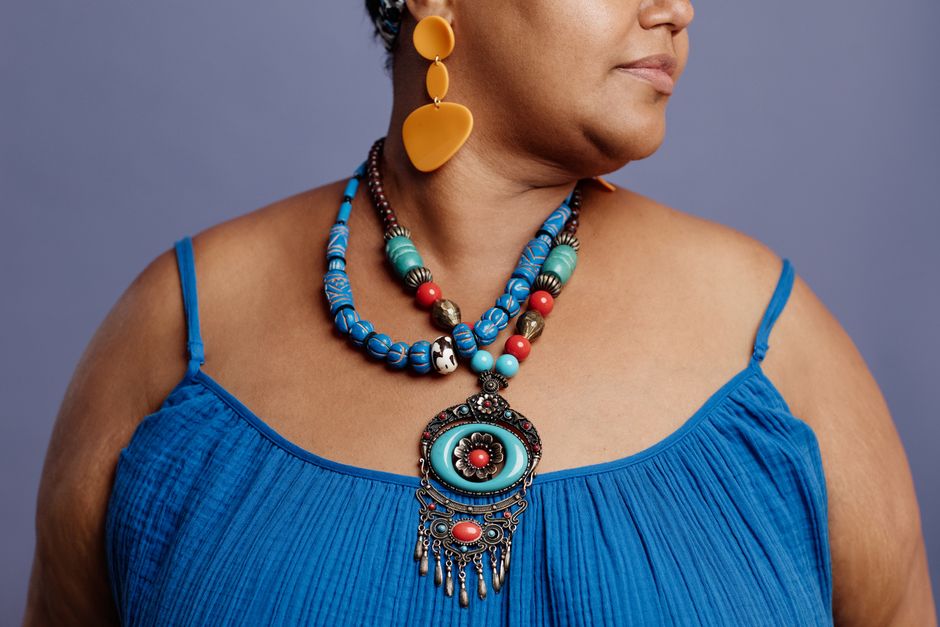 Close-up of a fashionable woman wearing colorful ethnic jewelry and a blue dress on a mute