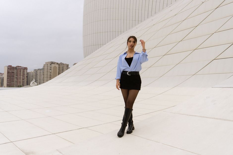 A stylish woman poses against a modern architectural backdrop, showcasing contemporary fashion.