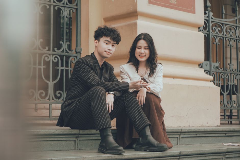 Charming couple sitting on decorative stairs in Hanoi, Vietnam, enjoying a relaxed moment.