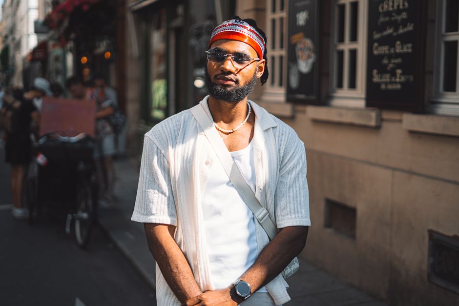 Street portrait of a fashionable man with sunglasses and headband in an urban setting.