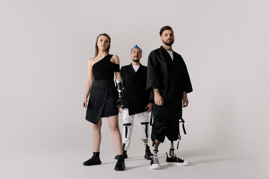 Diverse group showcasing prosthetic limbs in modern fashion on a white backdrop.