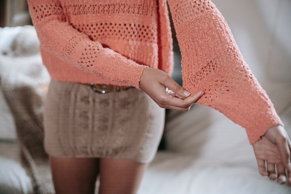 High angle of crop anonymous ethnic female wearing knitted sweater and skirt demonstrating