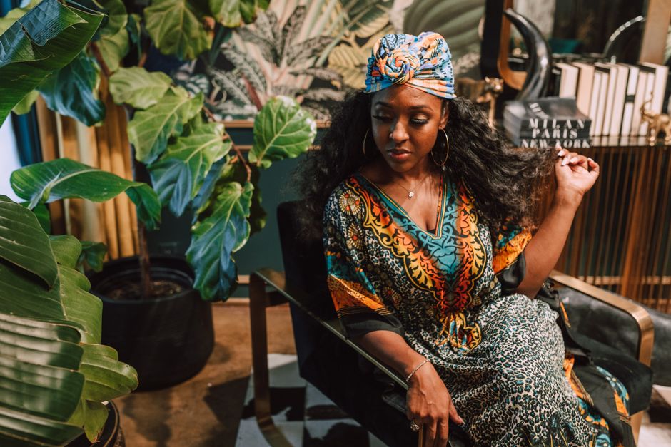 Beautiful woman in vibrant traditional attire amidst indoor greenery, exuding grace and elegance.