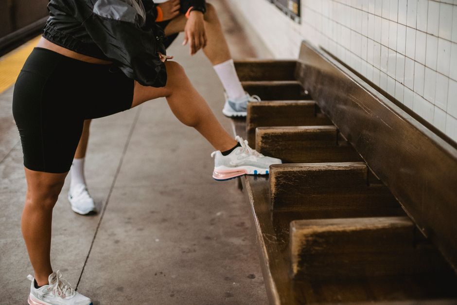 Two adults exercising with lunges on a subway bench, focusing on leg workout.