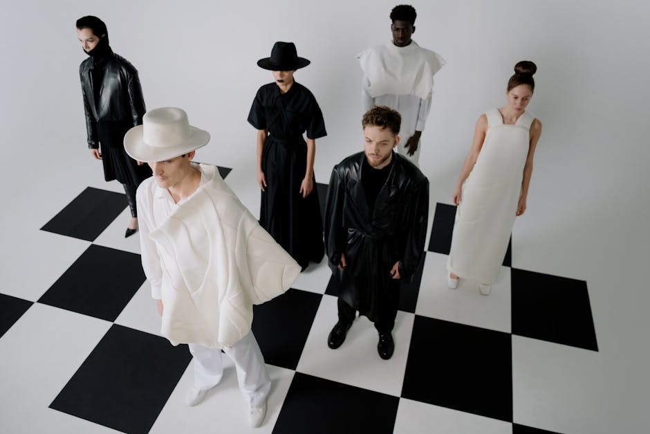 High-fashion models wear monochrome outfits on a chessboard pattern floor, showcasing diversity and style.
