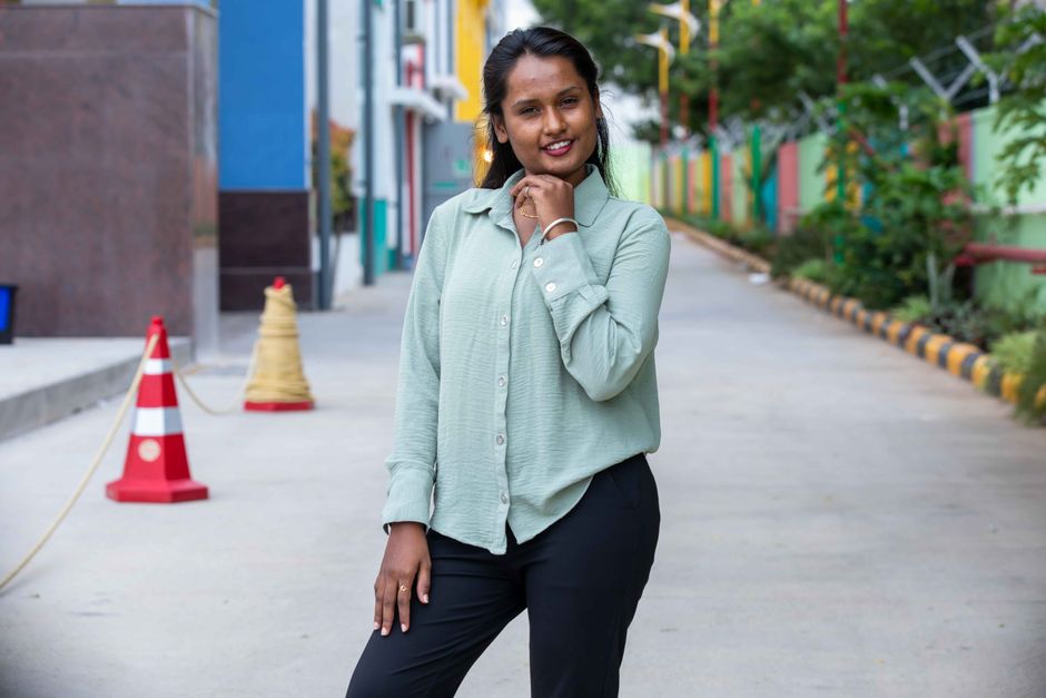 Portrait of a woman standing confidently on a colorful city street, smiling at the camera.