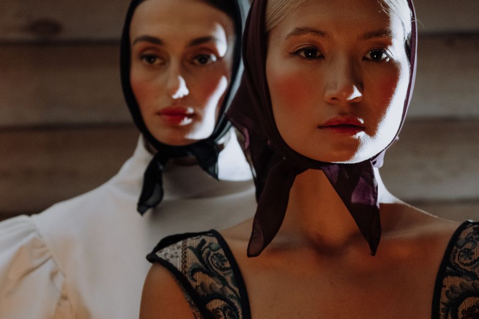 Close-up portrait of two women wearing vintage-style headscarves in soft lighting.
