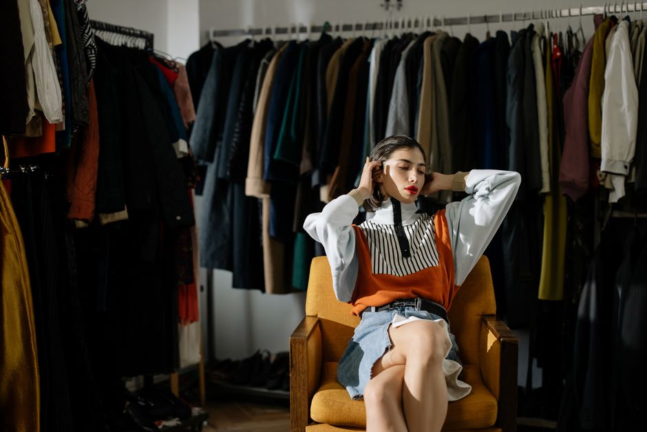 A stylish female model sits in a retro wardrobe setup.