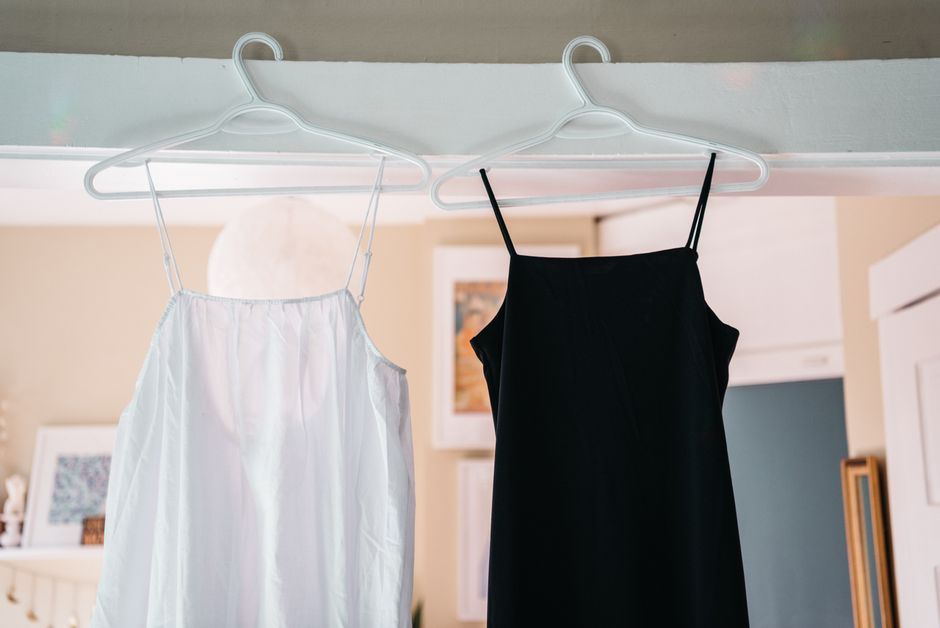 Minimalist display of black and white spaghetti strap dresses hanging indoors.