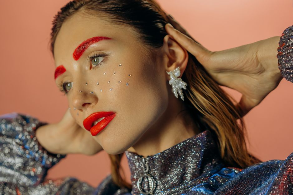 Striking portrait of a woman with bold red makeup and glitter accents, exuding elegance and modern style.
