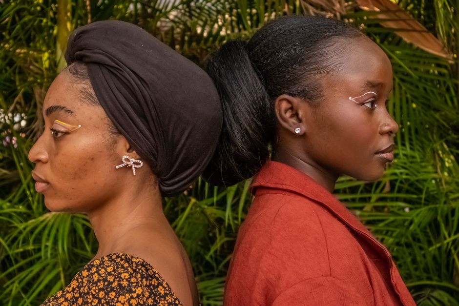 Two women stand back-to-back in a stylish outdoor setting, showcasing modern fashion and m