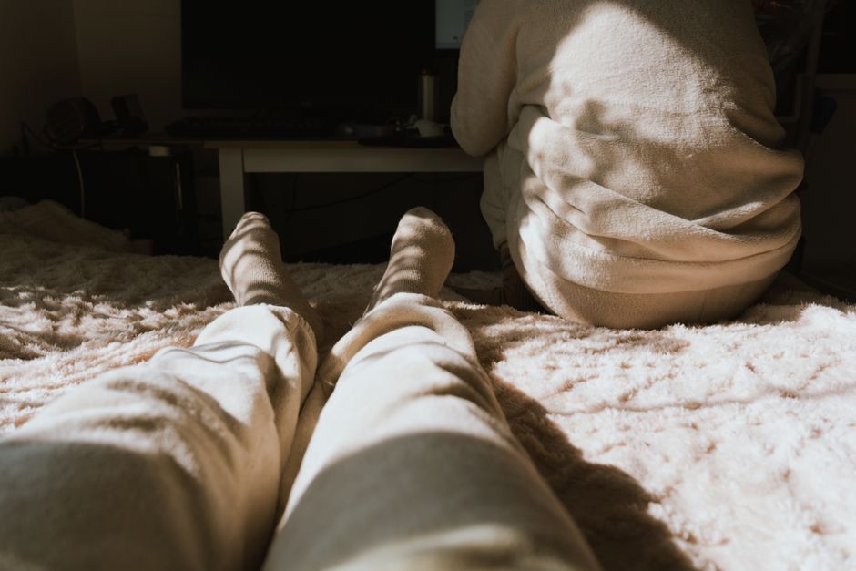 A cozy indoor morning scene with two people relaxing, bathed in warm sunlight and soft shadows.